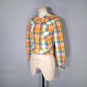 May include: A colorful plaid shirt with long sleeves, a collar, and a single pocket. The shirt features a vibrant pattern of orange, yellow, green, blue, and red. The shirt is displayed on a mannequin.