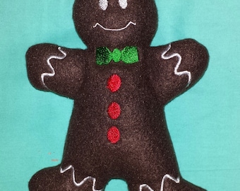 May include: A brown gingerbread man plush toy with white icing details, green bow tie, and red buttons.