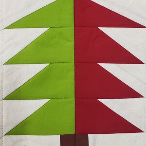 Può includere: Un design di albero di Natale trapuntato, con una divisione simmetrica. Una metà è verde brillante, l'altra rossa festosa. Il tronco dell'albero è marrone, su sfondo bianco. Il tessuto ha una sottile texture glitterata.