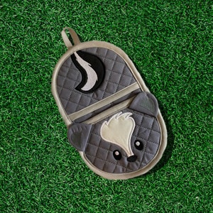 May include: Gray quilted oven mitt with a white and black embroidered skunk design. The skunk has a white stripe down its back and a black nose.