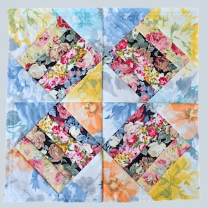Può includere: Una trapunta patchwork con un motivo a rombi. La trapunta è realizzata con diversi tessuti floreali in tonalità di blu, giallo, rosa e verde.