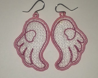 Könnte beinhalten: Ein Paar rosa und weiße Engelsflügel-Ohrringe. Die Flügel sind aus zarter Spitze und haben einen rosa Umriss.