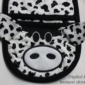 May include: Black and white cow-print oven mitt with a black border and a cute cow face with black eyes and nostrils.