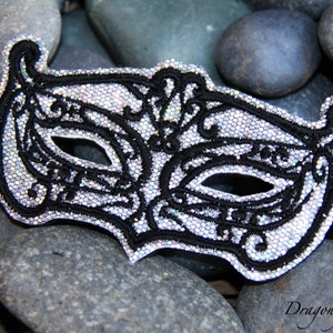 May include: A silver and black masquerade mask with intricate details and a sparkly finish.