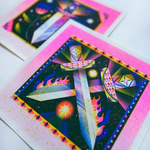 May include: Two pink and white prints with geometric designs featuring swords, flames, and stars. The designs are in shades of blue, green, yellow, and white.