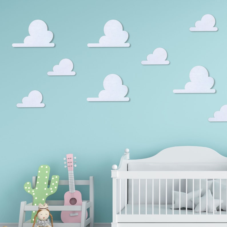 May include: A white cot with a white mattress and white bedding. The cot is in a room with a light blue wall and white clouds on the wall. There is a pink guitar and a green cactus in the room.