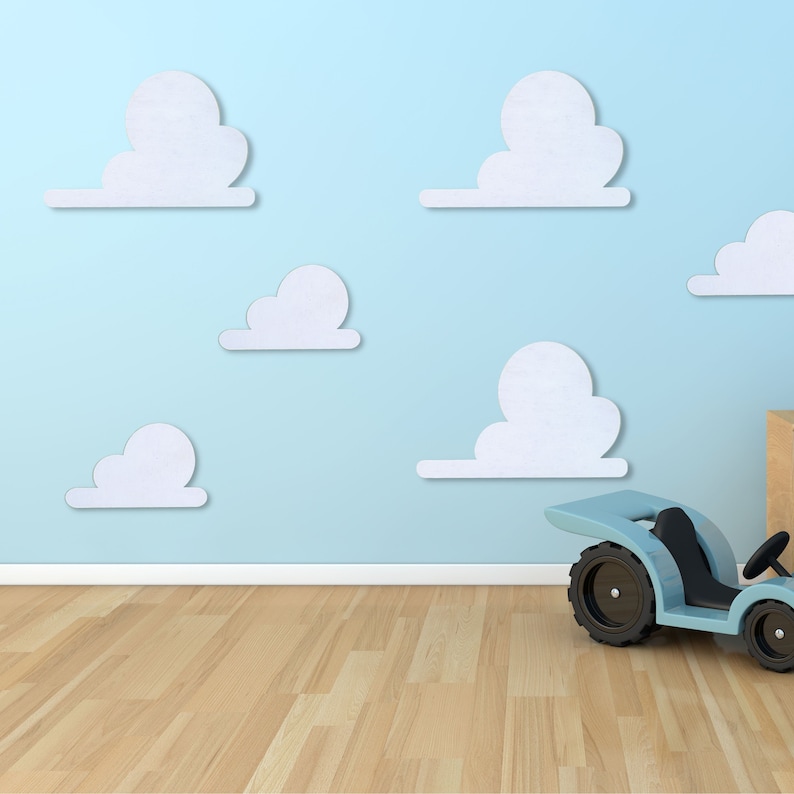 May include: A light blue toy car with black wheels sits on a light wood floor in front of a light blue wall with white paper cloud cutouts.