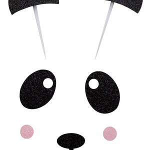 May include: Black and white panda face with glitter details. The panda has black ears, eyes, nose, and mouth. The face has two pink cheeks.