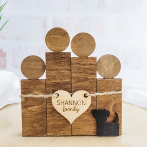 Puede incluir: Figurita de familia de madera con cinco figuras, incluyendo un perro, y una etiqueta en forma de corazón que dice "Shannon family".