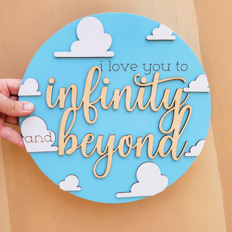 May include: A round, light blue wooden sign with white cloud cutouts. The sign features the phrase "i love you to infinity and beyond" in a cursive font. The sign is a decorative item.