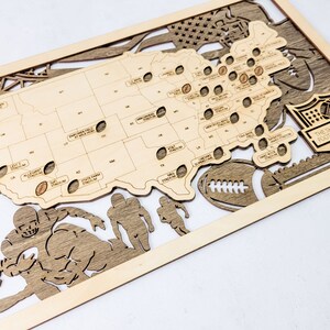 K&ouml;nnte beinhalten: Wandkunst aus Holz mit einer Karte der Vereinigten Staaten und den Standorten von Footballstadien. Enth&auml;lt Footballspieler-Silhouetten, einen Football und das NFL-Logo. Hergestellt aus hellem und dunklem Holz.