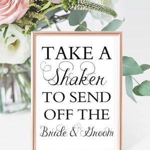 May include: A white sign with a rose gold frame that says "Take a Shaker to Send Off the Bride & Groom".
