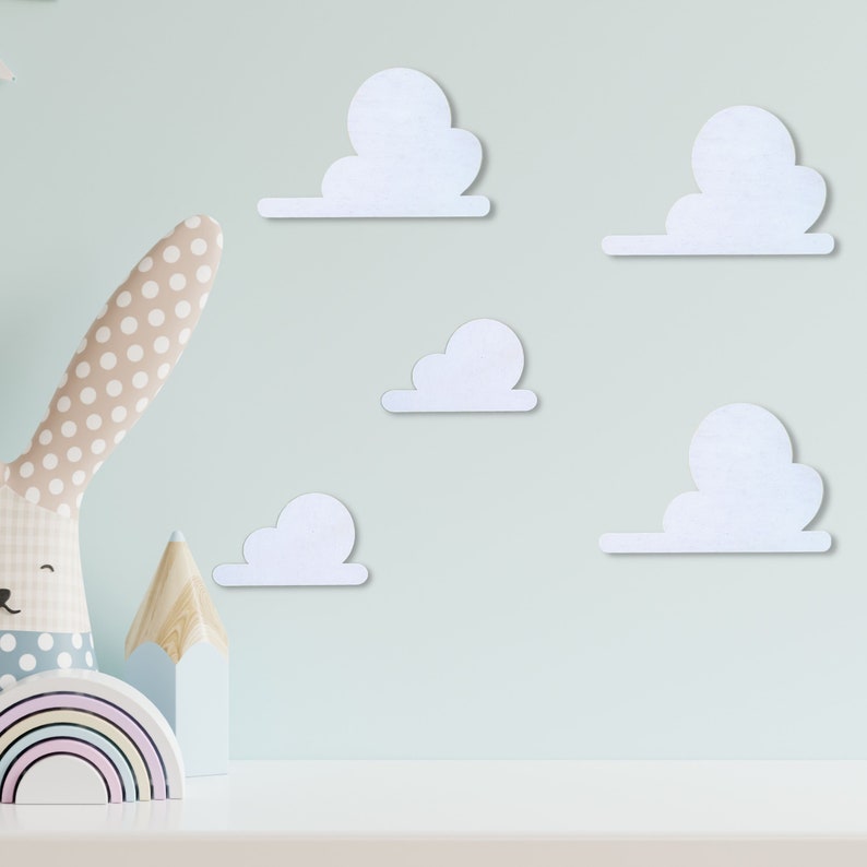 May include: Five white felt clouds of varying sizes are adhered to a light blue wall. The clouds are arranged in a staggered pattern.