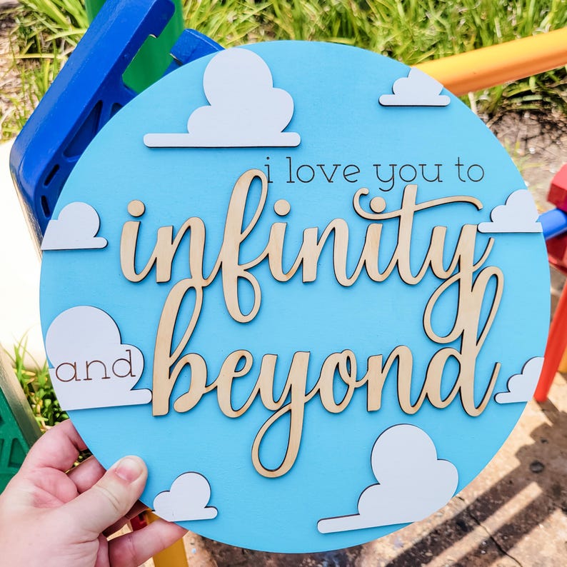 May include: A round, light blue wooden sign with the phrase "i love you to infinity and beyond" in cursive and block letters. White cloud cutouts are placed around the edge of the sign.