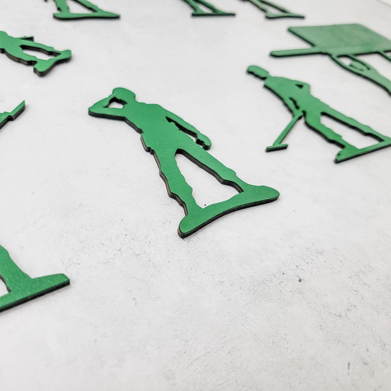 Puede incluir: Recortes de soldados de juguete verdes en varias poses, incluyendo saludar y apuntar. Los recortes est&aacute;n dispuestos sobre una superficie blanca. Los soldados son de un color verde vibrante con bordes negros, creando un contraste distintivo.