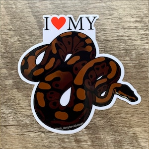 Op de afbeelding: Een witte sticker met een bruine en zwarte slangillustratie en de tekst "I ♥ MY" in rood en zwart.
