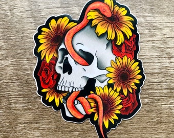 May include: A sticker featuring a white skull with a red snake wrapped around it. The skull is surrounded by yellow sunflowers and red roses.
