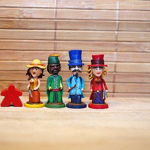 May include: A collection of four miniature figurines, each with unique attire and a distinct hat. The figures are painted in vibrant colors, including red, green, blue, and yellow. A red wooden game piece is also present.
