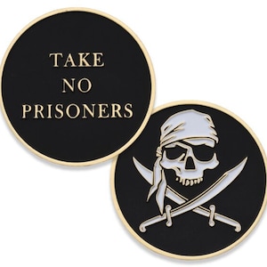 Puede incluir: Dos monedas de desafío redondas de metal negro. Un lado presenta el texto "TAKE NO PRISONERS" en letras doradas. El otro lado presenta una calavera y huesos cruzados blancos con una bandana blanca en la calavera.