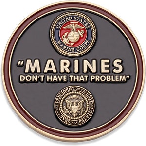 May include: A round, black coin with gold and maroon trim. The coin features the text "MARINES DON'T HAVE THAT PROBLEM" in gold lettering. The United States Marine Corps emblem and the Presidential Seal are also displayed.