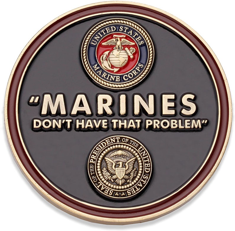 May include: A round, black coin with gold and maroon trim. The coin features the text "MARINES DON'T HAVE THAT PROBLEM" in gold lettering. The United States Marine Corps emblem and the Presidential Seal are also displayed.