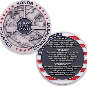 May include: A silver US Navy challenge coin featuring naval vessels, aircraft, and the text "US Navy Core Values". The coin also displays the words "Honor", "Courage", and "Commitment" with their definitions. The coin has a red, white, and blue border.