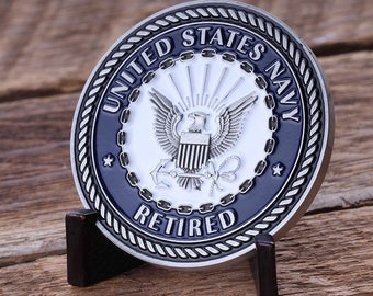 May include: A silver and blue United States Navy challenge coin with a rope border and the words "United States Navy" and "Retired".