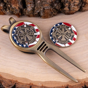 May include: A bronze-colored golf divot repair tool and coin set. The coin and tool feature a red, white, and blue design with the words "FIRE RESCUE" and a firefighter emblem. The tool has a fork design.