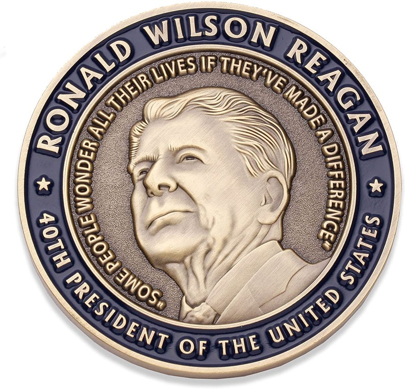 May include: A bronze-colored commemorative coin featuring a portrait of Ronald Wilson Reagan. The coin's outer ring is dark blue with the text "RONALD WILSON REAGAN" and "PRESIDENT OF THE UNITED STATES." The coin also includes the quote, "SOME PEOPLE WONDER ALL THEIR LIVES IF THEY'VE MADE A DIFFERENCE."