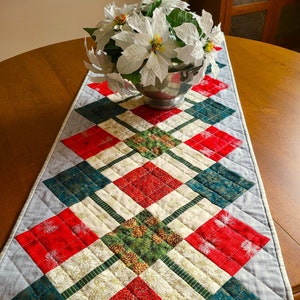 Quilted holiday table runner in green, red and cream Christmas prints with gold and silver metallic accents