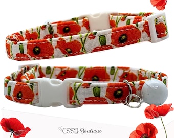 May include: Two cat collars with a white background and a pattern of red poppies. The collars have white plastic buckles and one has a small white bell attached. The text "CSSJ Boutique" is at the bottom.