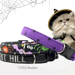May include: Two pet collars with Halloween themes. One collar is purple with black polka dots. The other is black with a pattern of orange spiders, green spiders, and purple bats, featuring the text "SILENT HILL" and a black plastic buckle.