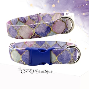May include: Purple and gold dog collar with a blue buckle and a silver D-ring. The collar has a watercolor pattern with geometric shapes.