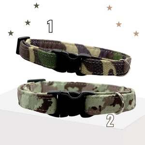 May include: Two pet collars labeled 1 and 2. Collar 1 features a dark green, brown, and black camouflage pattern. Collar 2 displays a lighter sage green, brown, and tan camouflage print. Both collars include a black plastic buckle and a metal D-ring.