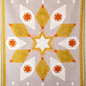 Può includere: Una trapunta fatta a mano con un design a stella centrale. La trapunta presenta uno sfondo grigio con una grande stella composta da forme geometriche bianche, arancioni e dorate. Il bordo è un motivo ripetuto di triangoli dorati. Un elemento di arredo per la casa.
