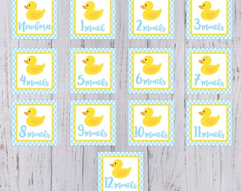 Op de afbeelding: Twaalf gele rubberen eendjes baby mijlpaal kaarten met blauw-wit geruite achtergronden. De kaarten zijn genummerd van pasgeborene tot 12 maanden.