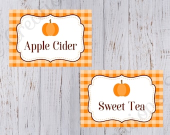 Op de afbeelding: Twee oranje en witte gingham-printbare voedseletiketten met een pompoenpictogram en tekst. Het bovenste etiket zegt "Appelcider" en het onderste etiket zegt "Zoete thee".