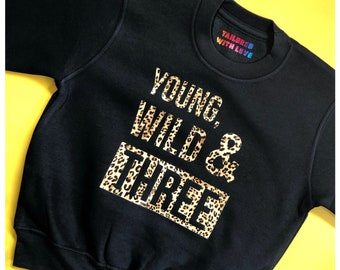 May include: Black sweatshirt with a leopard print design that says "Young, Wild & Three".