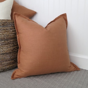 May include: A brown linen throw pillow with a subtle texture. The pillow is square and has a simple, understated design.