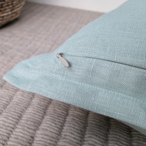 May include: A light blue pillow cover with a zipper closure. The pillow cover is made of a soft, textured fabric.