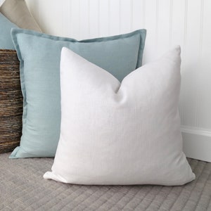 May include: Two decorative throw pillows, one light blue and one white, on a gray textured surface.