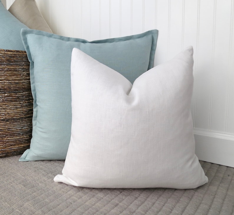May include: Two decorative throw pillows, one light blue and one white, on a gray textured surface.