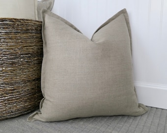 May include: A large, light beige linen pillow with a simple, rectangular shape. The pillow is made of a soft, natural fabric and has a subtle texture.