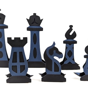 Könnte beinhalten: Ein Set aus sechs zweidimensionalen Schachfiguren aus Papier in Schwarz und Dunkelblau. Die Sammlung umfasst König, Dame, Turm, Springer, Läufer und Bauer, jeweils mit filigranen Ausschnitten und einem flachen Standfuß versehen.