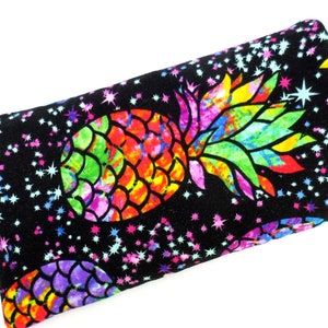 May include: A black fabric eye mask with a colourful pineapple print and a scattering of white stars.