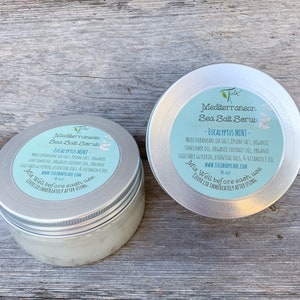 May include: Two silver jars of Mediterranean Sea Salt Scrub with Eucalyptus Mint scent. The jars are labeled with the product name, ingredients, and instructions to mix well before each use. The jars are 8 oz each.