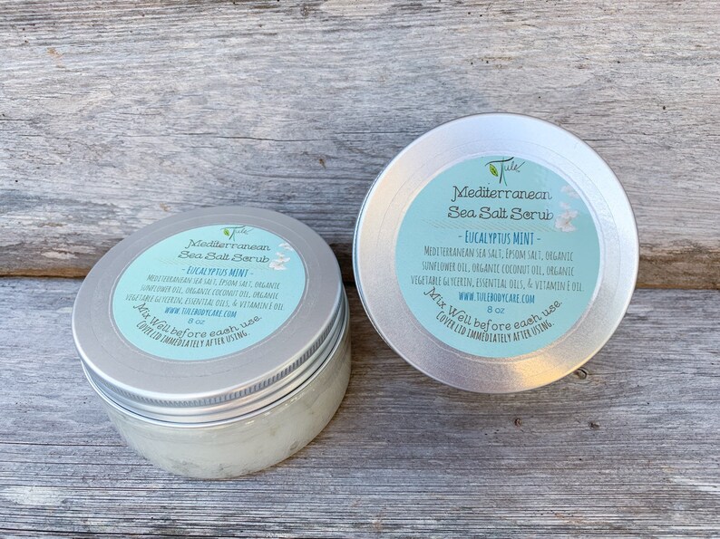 May include: Two silver jars of Mediterranean Sea Salt Scrub with Eucalyptus Mint scent. The jars are labeled with the product name, ingredients, and instructions to mix well before each use. The jars are 8 oz each.