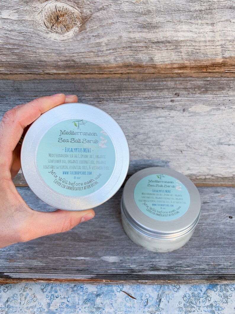 May include: Two silver tins of Mediterranean Sea Salt Scrub with Eucalyptus Mint scent. The label lists the ingredients: Mediterranean Sea Salt, Epsom Salt, Chegante Sunflower Oil, Organic Coconut Oil, Organic Vegetable Glycerin, Essential Oils, and Vitamin E Oil. The label also includes the website: www.tulebodycare.com. Each tin is 8 oz.
