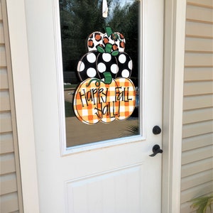 Peut inclure: Une porte blanche avec un panneau de verre repr&eacute;sentant une couronne de citrouille sur le th&egrave;me de l'automne avec le texte "Happy Fall Y'all!" en lettres vertes et noires.