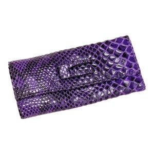 May include: A purple snakeskin clutch purse with a silver clasp.